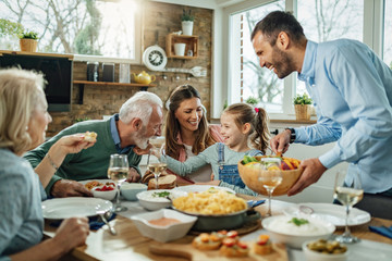Família reunidana mesa, comendo, conversando e dando lindas risadas.