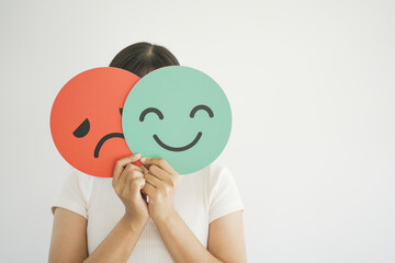 Mulher com dois emojis na frente do rosto. Um triste e outro alegre.