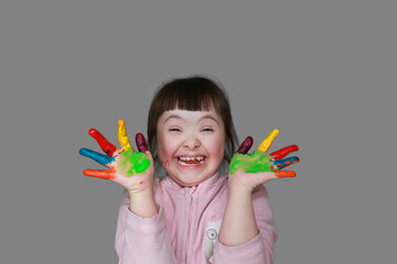 Imagem de uma menina com tinta multicolorida nas mãos, praticando brincadeiras, atividades físicas para crianças em casa